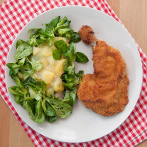 Un plato que contiene pollo empanizado con una ensalada