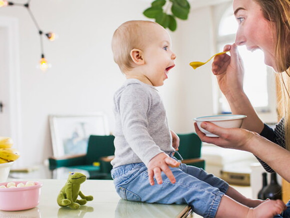 Bebé de 10 meses sentado comiendo con mamá