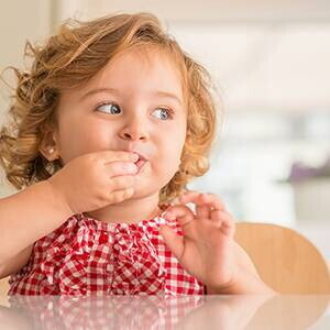 Niña comiendo con la mano