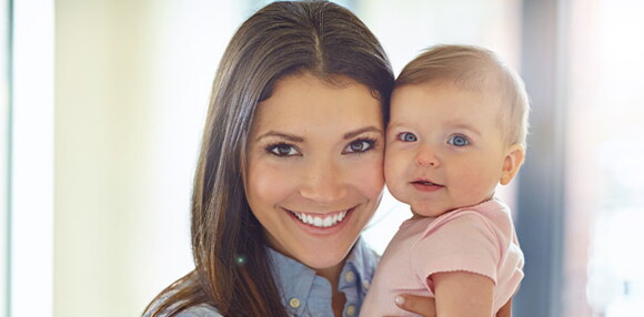 Mamá alzando a su bebé sonriente.